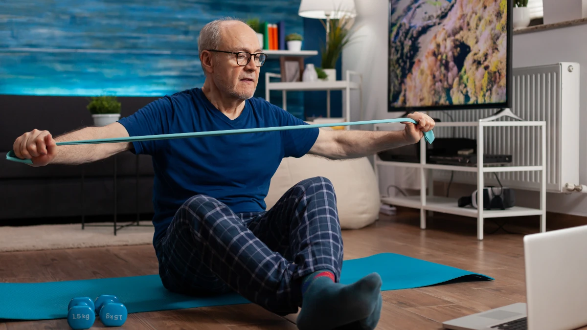 Senior man performing sit-to-stand exercise from a chair without using his hands